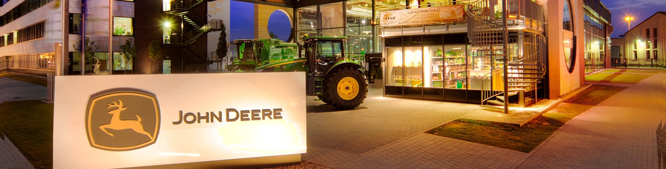 John Deere galvenās mītnes ēkas priekšējais skats ar dīķi un vītoliem priekšplānā