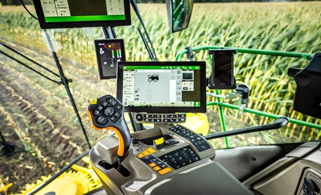 Pašgājējs lopbarības kombains F9 700 iekrauj Joskin piekabi, ko velk John Deere 6R traktors