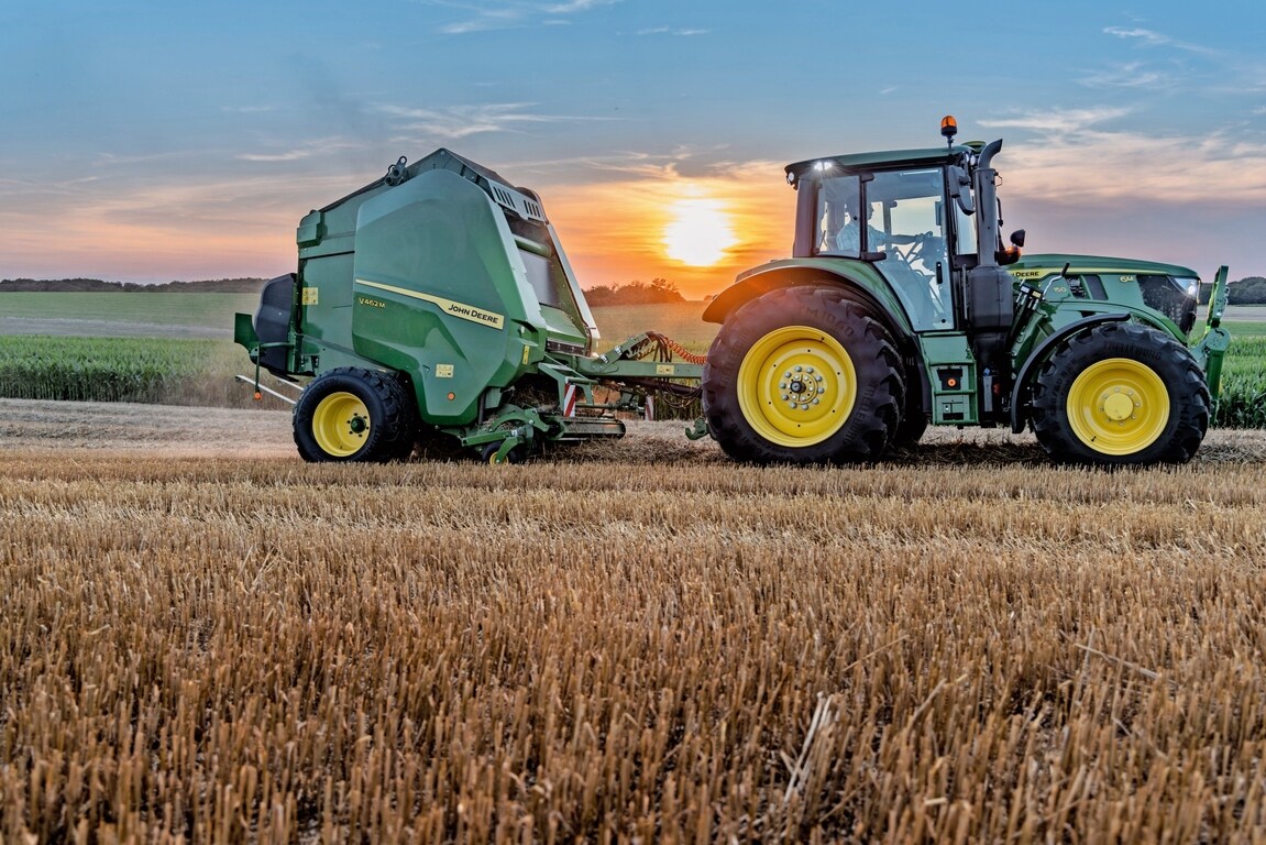 John Deere V462M uz salmu lauka, ko saulrietā velk John Deere 6M 150