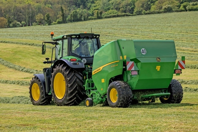 John Deere F442M presi velk John Deere 6M traktors kalnainā zāles laukā