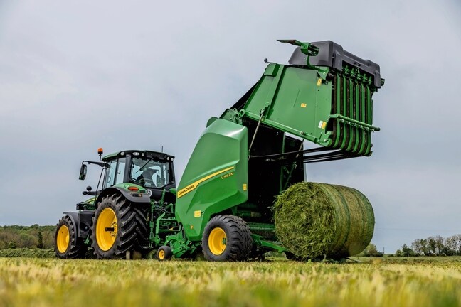John Deere V462M presi velk John Deere 6M traktors, izstumjot zāles rulli